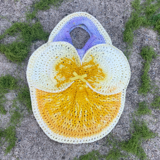 Crocheted bag with a yellow center and light yellow edges on a textured surface